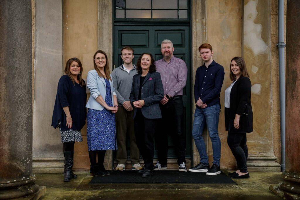 A photograph of the Fitwise Sales and Marketing team standing on the front step of Blackburn House